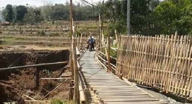Pengendara sepeda motor melewati jembatan bambu darurat. (Foto: Reza Abineri/ PanturaPost)