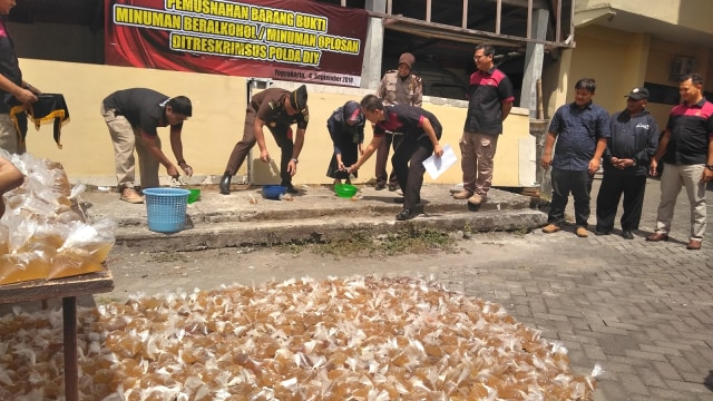 Jajaran Polda DIY memusnahkan 1.150 plastik minuman beralkohol (minol) oplosan atau yang biasa disebut langsung pening disingkat lapen, di Mapolda DIY, Yogyakarta, Selasa (04/09/2018). (Foto: Arfiansyah Panji Purnandaru /kumparan)