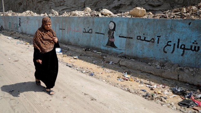 Seorang wanita berjalan melewati mural yang menggambarkan pesan pelecehan anti-seksual "Selamatkan jalan dari pelecehan" di jalan raya di Kairo, Mesir, Senin (03/09/2018). Foto: REUTERS/Amr Abdallah Dalsh