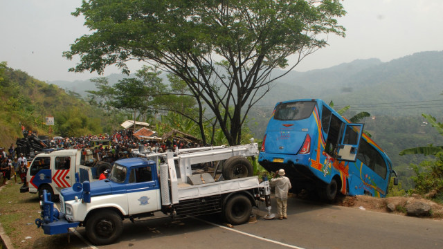 Petugas mengevakuasi mini bus berpenumpang puluhan wisatawan yang masuk jurang di Tanjakan Letter S, Sukabumi, Jawa Barat, Minggu (9/9). (Foto: Antara/Budiyanto)