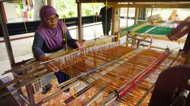 Pengrajin tenun songket Aceh, Jasmani Daud, sedang merajin tenun di tempat usahanya di Jalan Lambaro Angan, Desa Mireuk Taman, Kecamatan Darussalam,  Aceh Besar, Rabu (12/9/2018). (Foto: Zuhri Noviandi/kumparan)