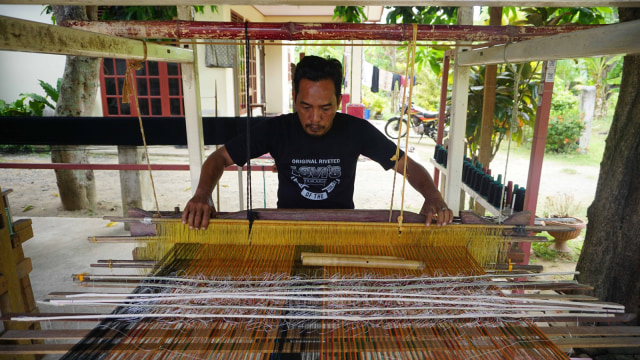 Pengrajin tenun songket Aceh, Pahriansyah, sedang merajin tenun di tempat usahanya di Jalan Lambaro Angan, Desa Mireuk Taman, Kecamatan Darussalam,  Aceh Besar, Rabu (12/9/2018). (Foto: Zuhri Noviandi/kumparan)