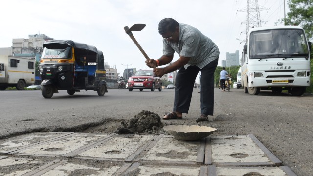 Aksi Dadarao Bilhore dalam menambal lubang jalanan di India. (Foto: AFP/INDRANIL MUKHERJEE )