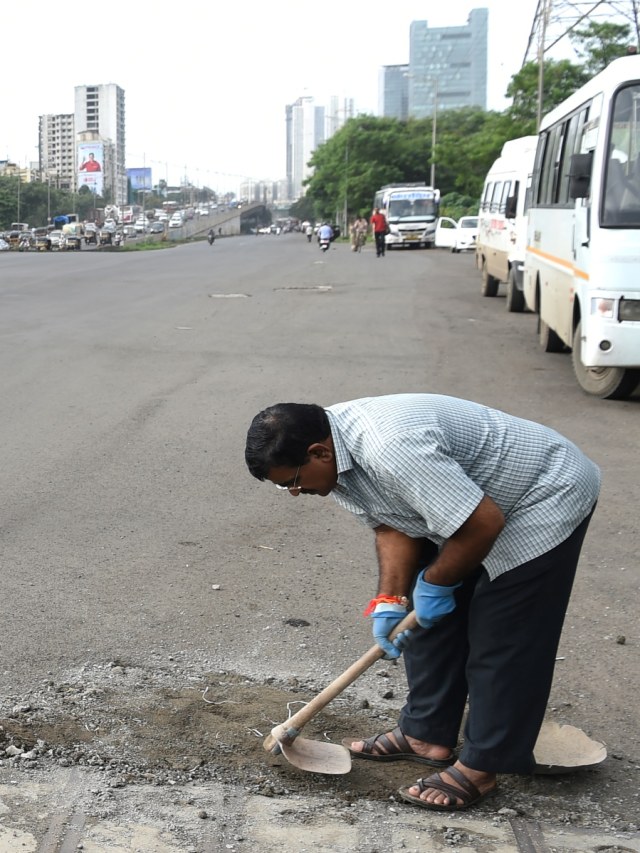 Dadarao Bilhore sedang menambal lubang jalanan di India. (Foto: AFP/INDRANIL MUKHERJEE )