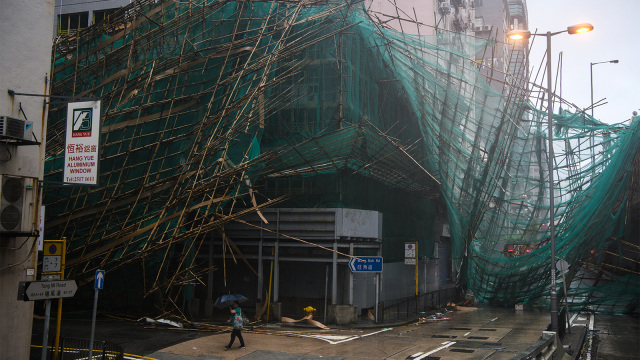 Warga melintasi gedung yang rusak dalam proses renovasi usai terjadi topan Mangkhut di Hong Kong. (Foto: AFP PHOTO / Anthony Wallace)