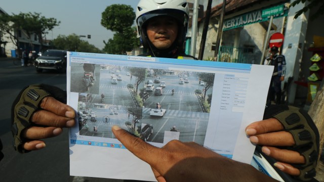 
Polisi menunjukkan bukti cetak pelanggar lalu lintas yang terekam kamera CCTV di Surabaya, Jawa Timur, Kamis (2/8/2018). Foto: ANTARA FOTO/Didik Suhartono