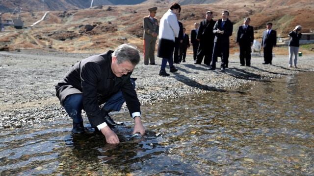 Presiden Korea Selatan, Moon Jae-in mengisi botol plastik dengan air dari danau Surga di Mt. Paektu, Korea Utara. (Foto: Pyeongyang Press Corps/Pool via REUTERS)