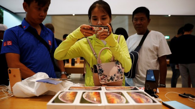 Pelanggan dari Vietnam mengambil foto pembelian iPhone XS mereka di Apple Store di Singapura. (Foto: REUTERS/Edgar Su)