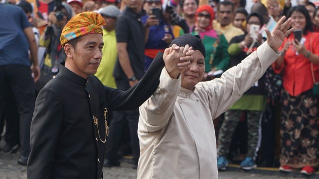 Jokowi (kiri) dan Prabowo (kanan) bergandengan usai menandatangani deklarasi kampanye damai Pemilu 2019 di Monas, Jakarta, Minggu (23/9/2018). (Foto: Fanny Kusumawardhani/kumparan)