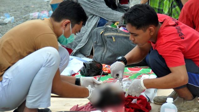 Tim medis menangani seorang anak yang menjadi korban gempa di Palu. (Foto: AFP/MUHAMMAD RIFKI)