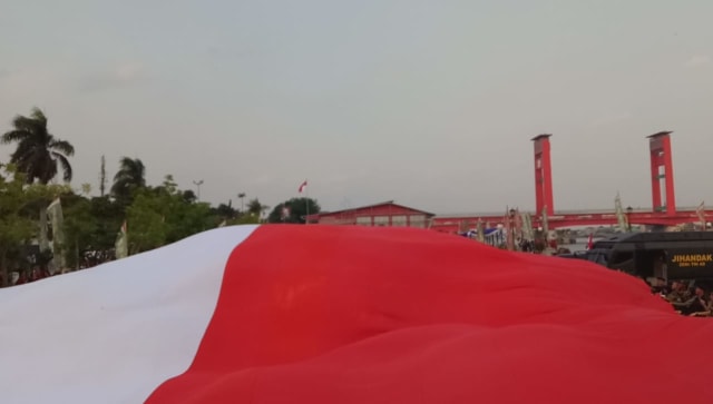 Pembentangan bendera 3000 meter persegi di Palembang dalam rangka Pawai Bendera HUT TNI ke-73 di Palembang, Sabtu (29/9/2018). (Foto: Adhim Mugni M/kumparan)
