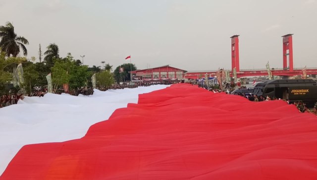 Pembentangan bendera 3000 meter persegi di Palembang dalam rangka Pawai Bendera HUT TNI ke-73 di Palembang, Sabtu (29/9/2018). (Foto: Adhim Mugni M/kumparan)