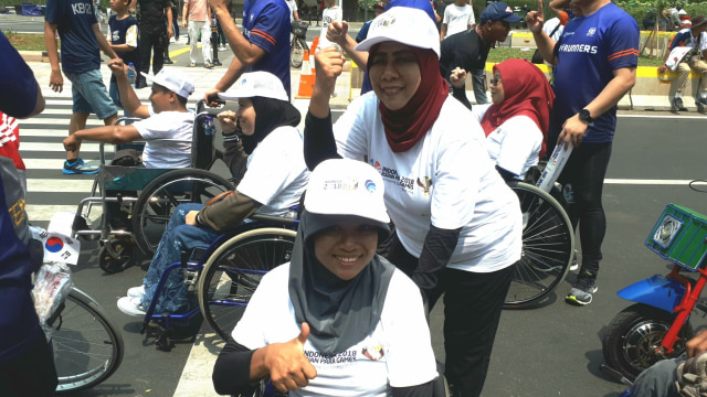 Anggota Perkumpulan Penyandang Disabilitas Indonesia (PPDI), Wati (kursi roda) dan Kasih, mengikuti Pawai Obor Asian Para Games 2018, di Bundaran HI, Jakarta, Minggu (30/9). (Foto: Karina Nur Shabrina/kumparan)