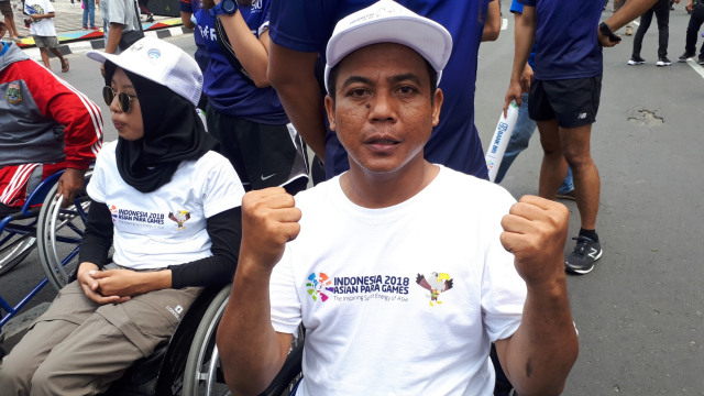 Anggota Perkumpulan Penyandang Disabilitas Indonesia (PPDI), Erwin, mengikuti Pawai Obor Asian Para Games 2018, di Bundaran HI, Jakarta, Minggu (30/9). (Foto: Karina Nur Shabrina/kumparan)