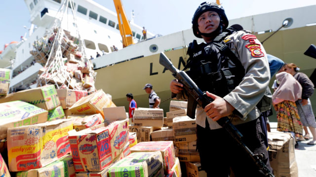 Polisi mengamankan aktivitas bongkar muat bantuan makanan untuk korban gempa dan tsunami Palu serta Donggala di Pelabuhan Kelas-III Pantoloan, Palu, Sulawesi Tengah, Senin (1/10). (Foto: ANTARA FOTO/Irwansyah Putra)