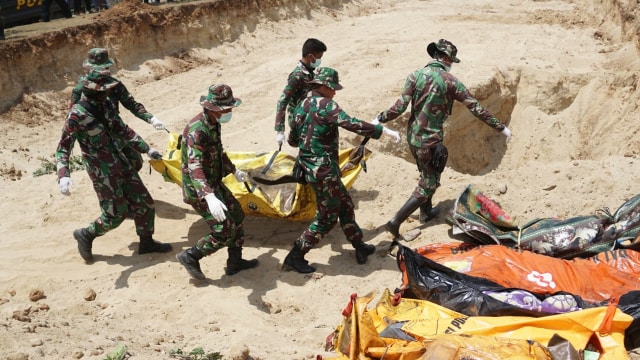 TNI membantu prosesi pemakaman masal korban gempa dan tsunami Palu. (Foto: Jamal Ramadhan/kumparan)