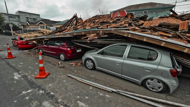 Sebuah bangunan menghancurkan mobil yang sedang berada di jalan akibat gempa di Selandia Baru (2/22/2011). (Foto: AFP/Logan Mcmillan)