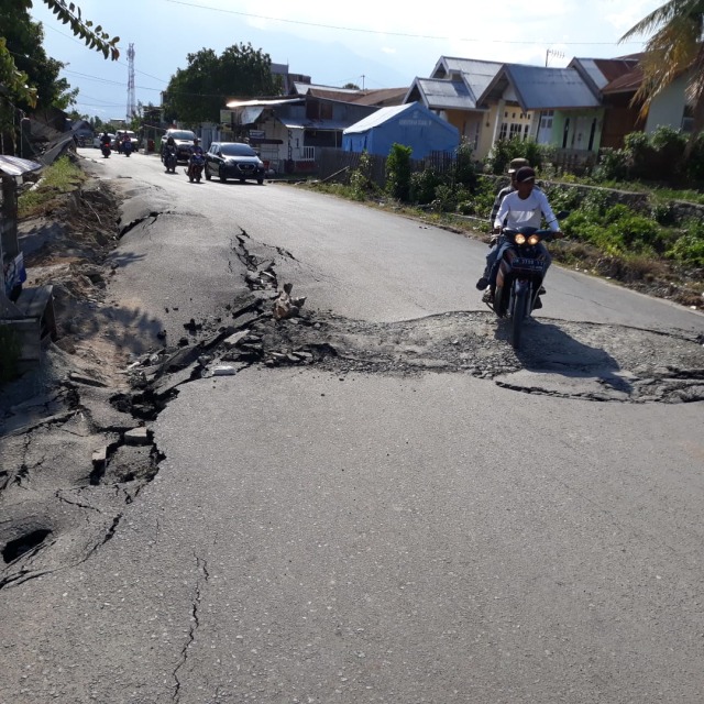 Warga melintasi jalan yang rusak di wilayah Kelurahan Tanamodindi, Kecamatan Mantikulore, Kota Palu, pascagempa Palu. (Foto: Dok: Amar Burase)