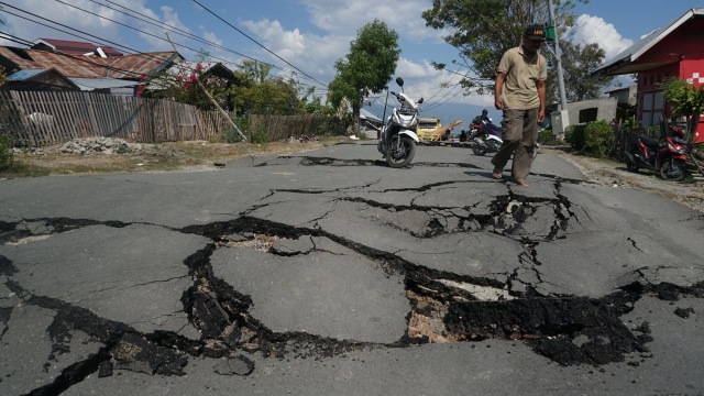 Warga melintasi jalan yang hancur di wilayah Balaroa akibat gempa bumi, Palu, Sulawesi Tengah. (Foto: Jamal Ramadhan/kumparan)