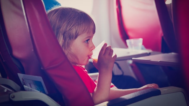 Anak kecil sedang minum dalam pesawat (Foto: Shutter Stock)