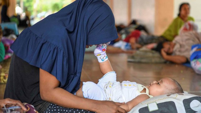 Ibu dan anak berada di tenda pengungsian di Lapangan Vatulemo, Palu, Sulawesi Tengah, Selasa (2/10).  (Foto: ANTARA FOTO/Hafidz Mubarak A)