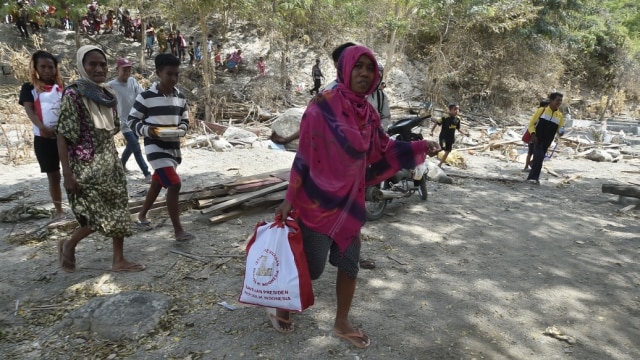 Warga korban gempa dan tsunami membawa bantuan dari Persiden Joko Widodo di Desa Loli Saluran, Donggala, Sulawesi Tengah, Rabu (3/10). (Foto: ANTARA FOTO/Muhammad Adimaja)