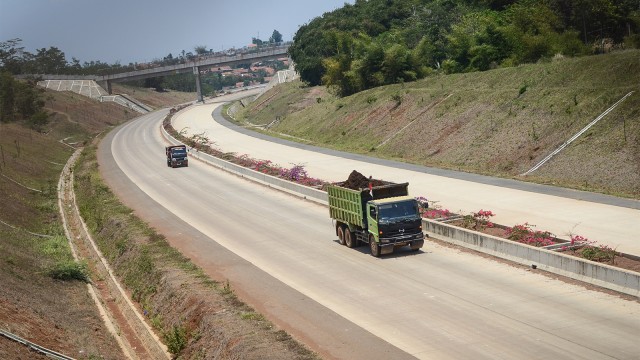 Pekerja membawa material proyek jalan tol Cileunyi-Sumedang-Dawuan (Cisumdawu) dengan truk di Pamulihan, Kabupaten Sumedang, Jawa Barat. Foto: ANTARA FOTO/Raisan Al Farisi