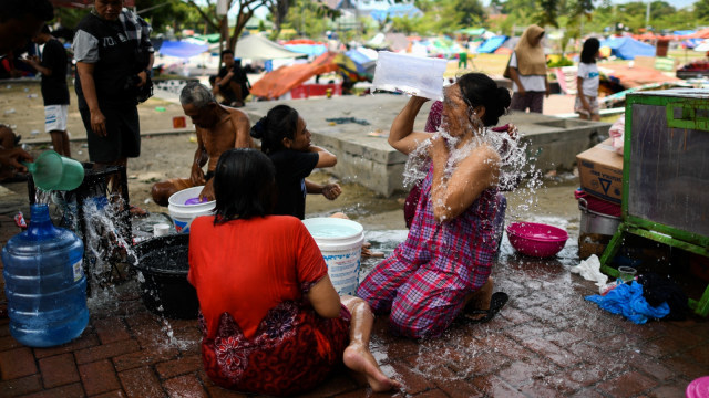 Pengungsi di Kantor Wali Kota Palu mandi setelah air bersih mulai lancar. (Foto: AFP/JEWEL SAMAD)