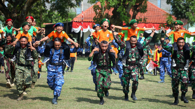 Siswa Sekolah Dasar bersama anggota TNI mengikuti lomba lari gendong saat merayakan HUT ke-73 TNI di Lapangan Makorem 074/Warastratama, Solo. (Foto: ANTARA FOTO/Maulana Surya)