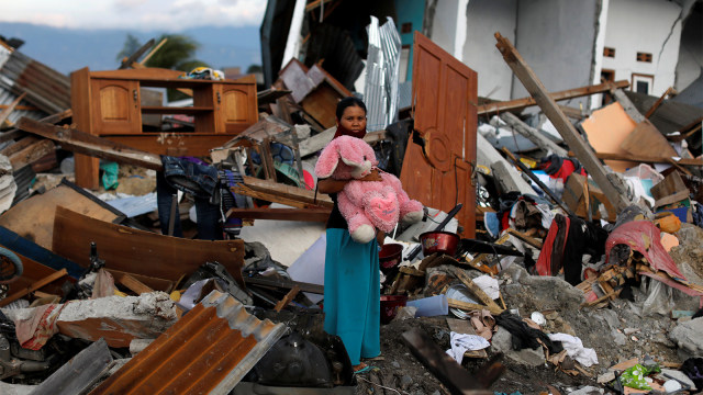 Seorang wanita memegang boneka kelinci yang ditemukan di rumahnya yang hancur akibat gempa bumi. Dia mangaku telah kehilangan ketiga anaknya dalam kejadian tersebut. (Foto: REUTERS / Jorge Silva)