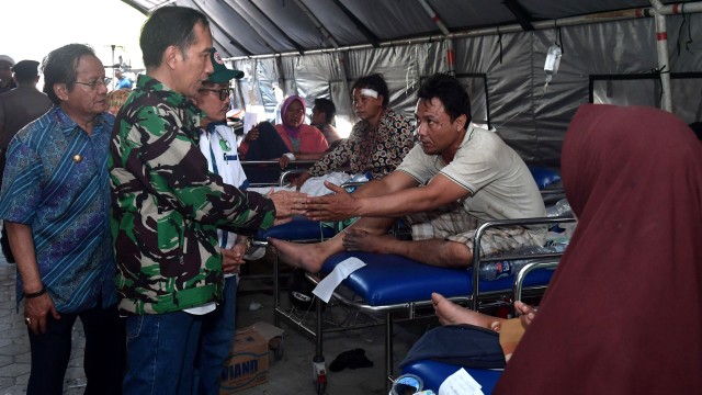 Presiden Joko Widodo didampingi Gubernur Sulawesi Tengah Longki Djanggola (batik biru) mengunjungi korban gempa bumi dan tsunami di Palu, Sulawesi Tengah, Minggu (30/9). (Foto: ANTARA FOTO/Biropers-Kris)