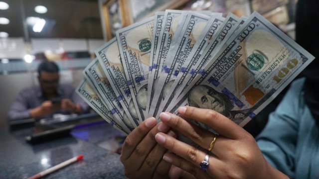 Petugas memperlihatkan pecahan uang dolar dan rupiah di salah satu tempat penukaran mata uang asing/money changer di Jakarta. Foto: Fanny Kusumawardhani/kumparan
