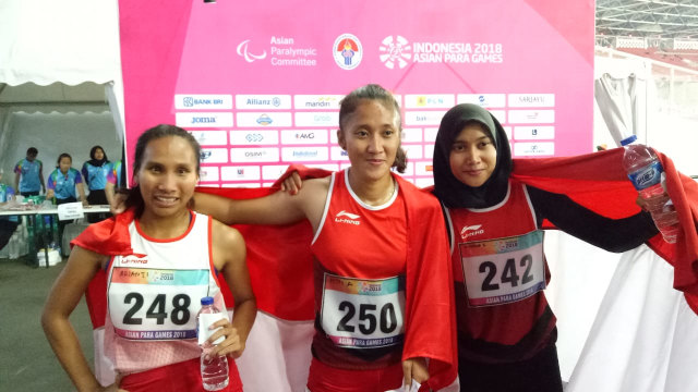 Ni Made Arianti (kiri, perak), Putri Aulia (tengah, emas), dan Endang Sari Sitorus (kanan, perunggu) berjaya di nomor lari 100 meter T13 putri. (Foto: Aditia Rizki Nugraha/kumparan)
