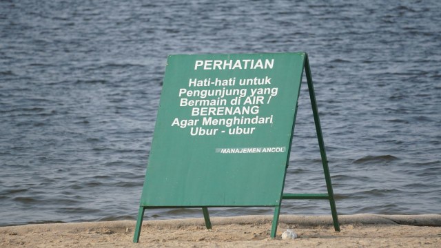 Papan peringatan untuk pengunjung agar waspada terhadap keberadaan ubur-ubur di Pantai Ancol. (Foto: Nugroho Sejati/kumparan)