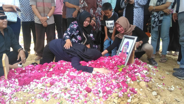 Roro Fitria peluk makam Ibunda di TPU Pemerintah Kabupaten (Pemkab) Sleman di Beran, Margodadi, Seyegan, Sleman, Selasa (16/10/2018). (Foto: Arfiansyah Panji Purnandaru/kumparan)