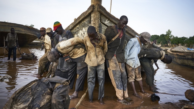 Pekerja mendorong perahu untuk mencari pasir di sungai Niger. (Foto: Michele Cattani / AFP)