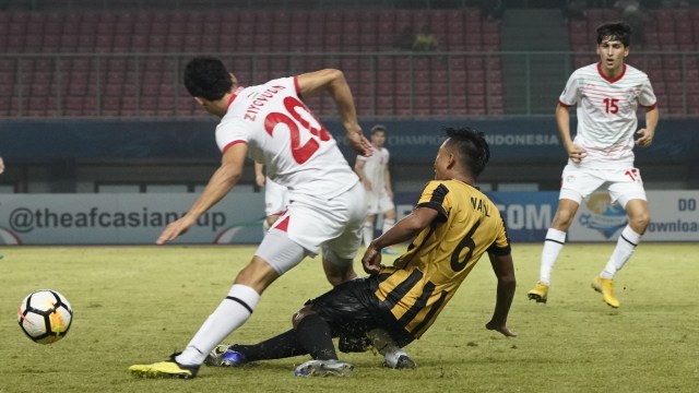 Pemain Tajikistan U-19, Fuzaylov Ziyovuddin (20), mendapat tekel horor dari pemain Malaysia, Nabil Hakim Bokhari (6). (Foto: Dok. AFC)