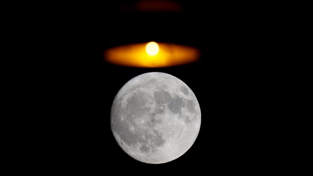 Bulan terlihat di atas tanda neon farmasi di pusat kota Roma, Italia. (Foto: REUTERS/Max Rossi)