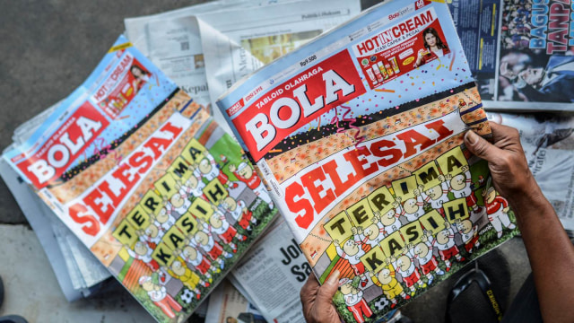 Loper koran merapikan Tabloid Olahraga Bola edisi penutup atau terbitan terakhir yang dijualnya di kawasan Kwitang, Senen, Jakarta, Jumat (26/10/2018). (Foto:  ANTARA FOTO/Aprillio Akbar)