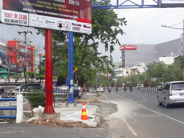 Reklame yang masih berdiri di tengah proyek trotoar ramah difabel di Jalan Ahmad Yani kilometer 2, Kota Banjarmasin. (Foto: Anang Fadhilah/banjarhits.id)