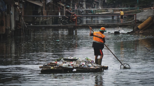 Pekerja Dinas Lingkungan Hidup membersihkan sampah di sungai belakang permukiman warga samping rel kereta di Jalan Tanjung Selor, Jakarta Pusat, Sabtu (27/10/2018). Foto: Jamal Ramadhan/kumparan