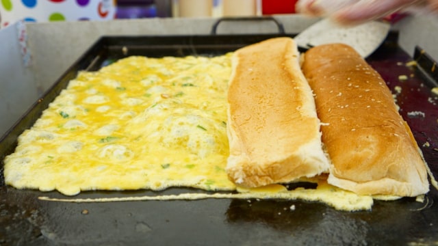 Saat membuat roti John, letakkan dan tekan roti di atas telur (Foto: Shutterstock)
