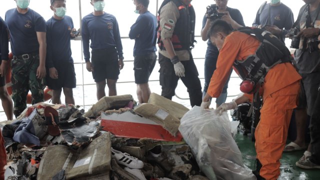Sejumlah anggota Basarnas membawa puing-puing pecahan pesawat Lion Air JT-610 dan jenazah korban ke dalam kapal induk Basarnas di perairan Tanjung Pakis, Karawang, Selasa (30/10). (Foto: Aditia Noviansyah/kumparan)