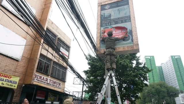 Petugas Badan Pajak dan Retribusi Daerah (BPRD) DKI Jakarta memasang tanda stiker penunggak pajak didaerah DKI Jakarta, Rabu (7/11/2018). (Foto: Helmi Afandi Abdullah/kumparan)