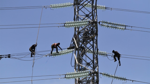 Pekerja memasang jaringan kabel ke tower milik PT PLN Persero. Foto: ANTARA FOTO/Jojon