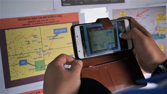 Petugas memotret peta lokasi jatuhnya pesawat Lion Air JT 610 di Posko Evakuasi, JICT, Jakarta. (Foto: Jamal Ramadhan/kumparan)