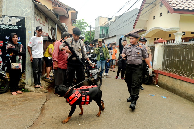 Polisi melakukan penyisiran dengan anjing pelacak di sekitar lokasi perisitiwa pembunuhan satu keluarga, di kawasan Jatirahayu, Bekasi, Jawa Barat, Selasa (13/11/2018). (Foto: ANTARA FOTO/Risky Andrianto)