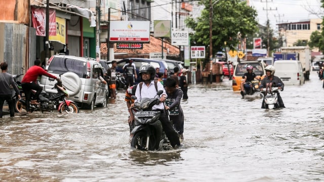 Sejumlah pengendara mendorong kendaraannya saat melintasi jalan yang terendam banjir dikawasan Sekip Bendung, Palembang, Sumatera Selatan, Selasa (13/11/2018).  (Foto: ANTARA FOTO/Nova Wahyudi)
