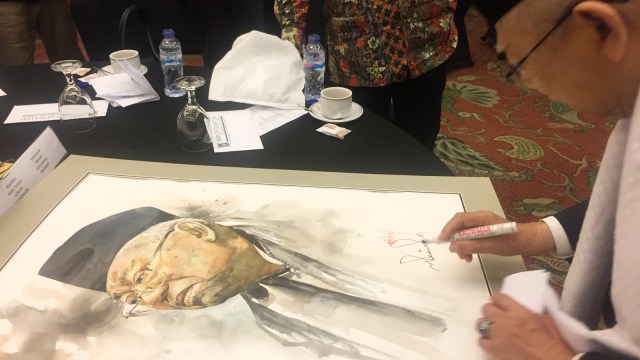 Ma’ruf Amin menandatangani lukisan yang dilelang. (Foto: Moh Fajri/kumparan)