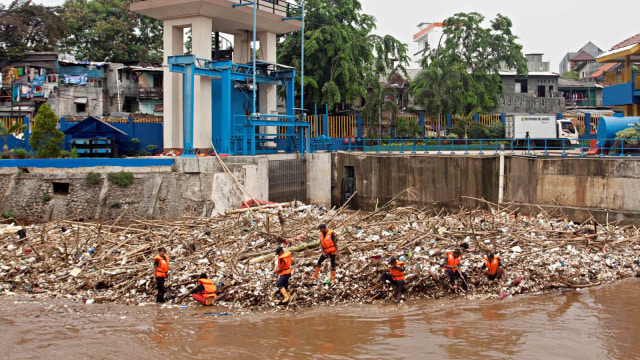 Petugas Dinas Kebersihan DKI Jakarta membersihkan sampah yang menumpuk di pintu air Manggarai, Jakarta, Senin (12/11/2018). (Foto: ANTARA FOTO/Galih Pradipta)